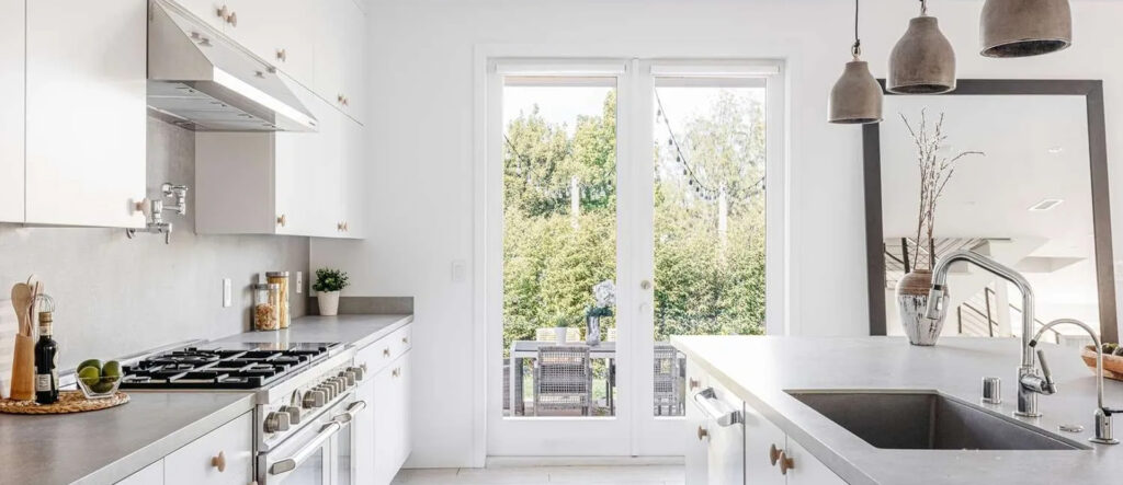 Bright kitchen with large glass doors opening to a green backyard.